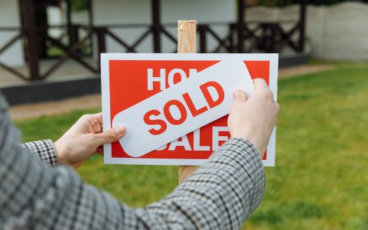 Shallow Focus Photo of a Realtor Posting a Sold Sticker