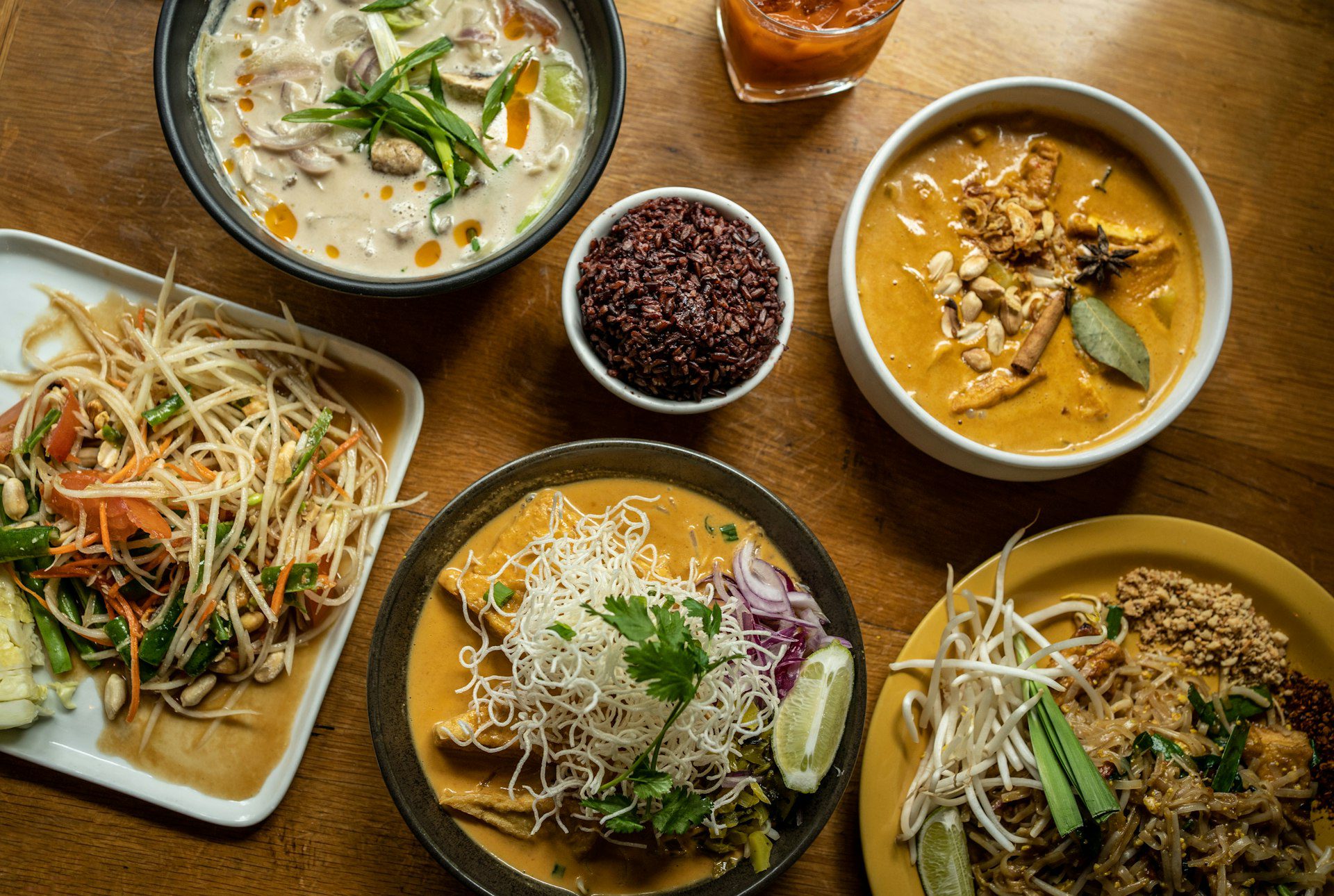 A shared table of Thai dishes including papaya salad and curry